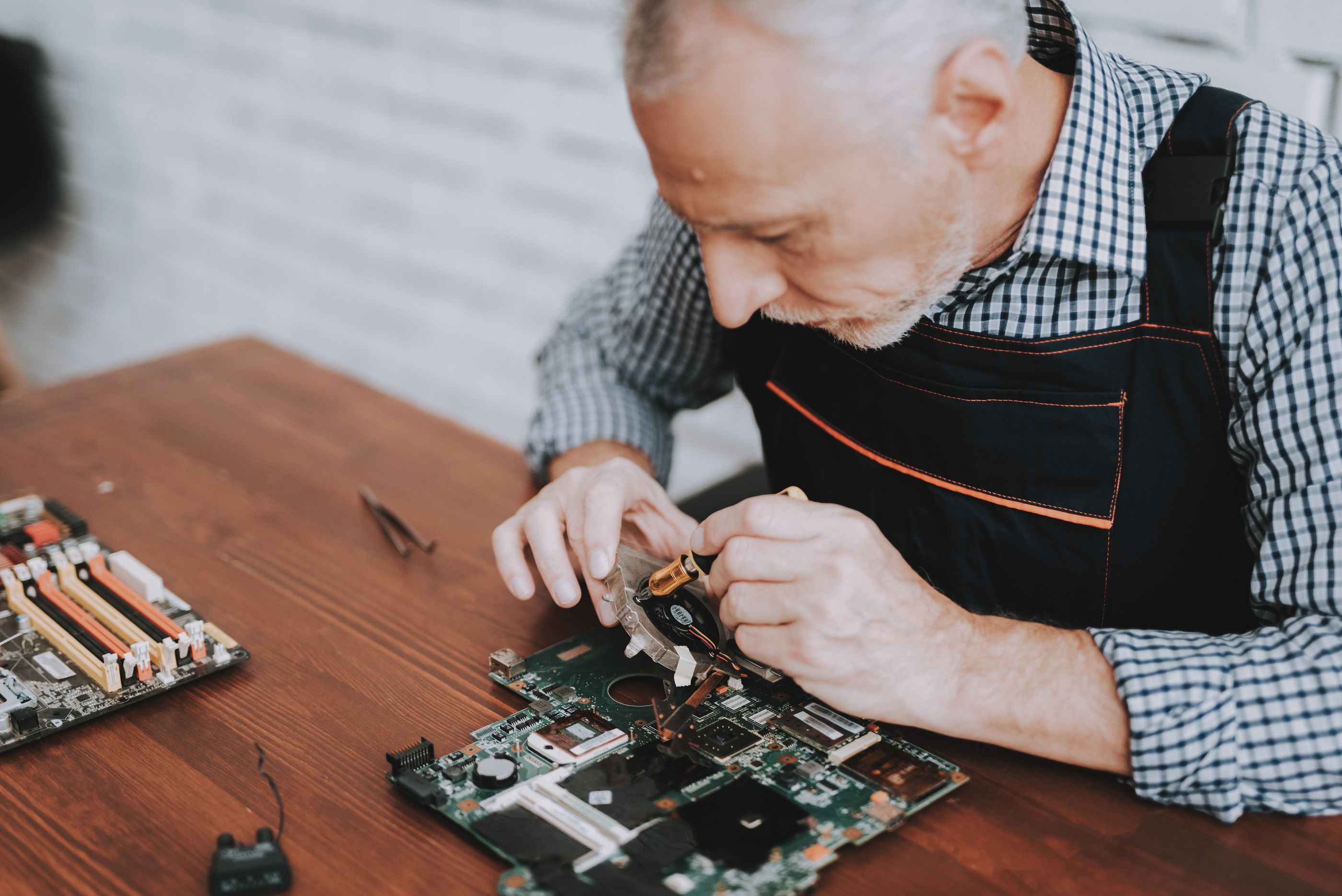 Trabajador sénior reparando una placa de ordenador.