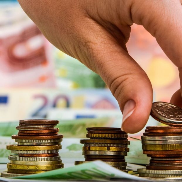 mujer colocando monedas euro en pilas