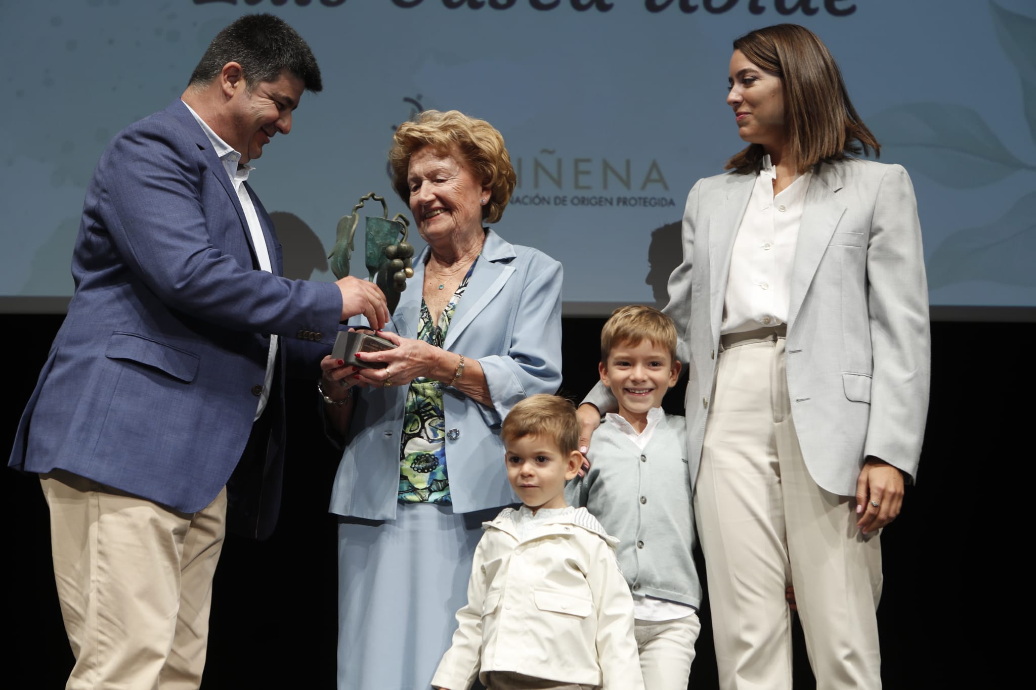 Homenaje de la DOP Cariñena a Luis Gasca. El presidente Antonio Ubide entrega galardón a la viuda María Pilar Gimeno, su nieta y bisnietos Foto: Cariñena