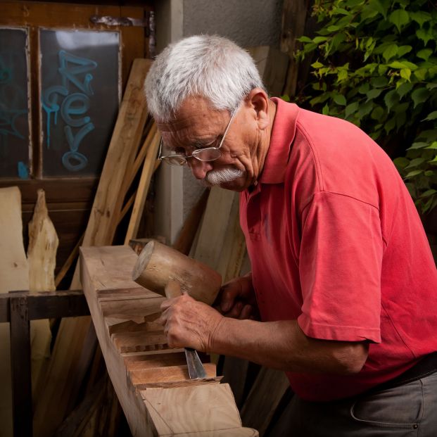 Trabajador sénior en su taller de tallado de madera.