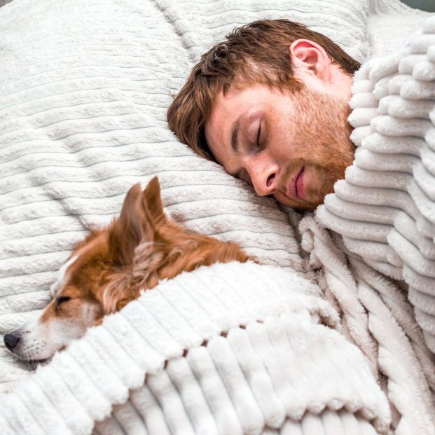 Hombre durmiendo en la cama con su perro