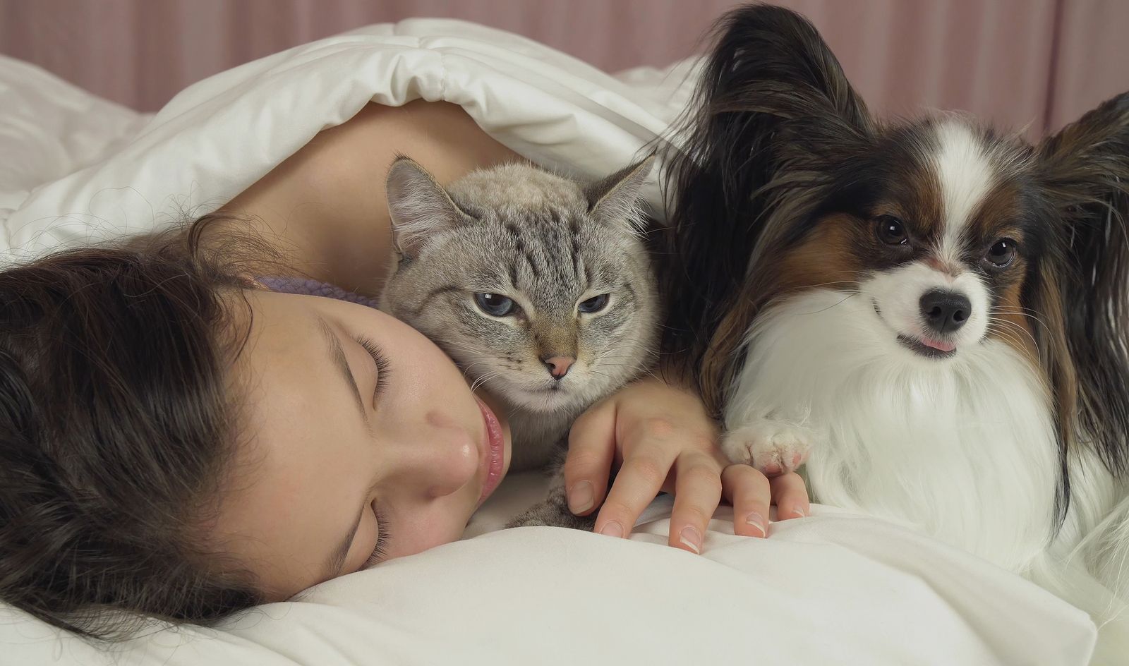 Mujer durmiendo con su perro y gato