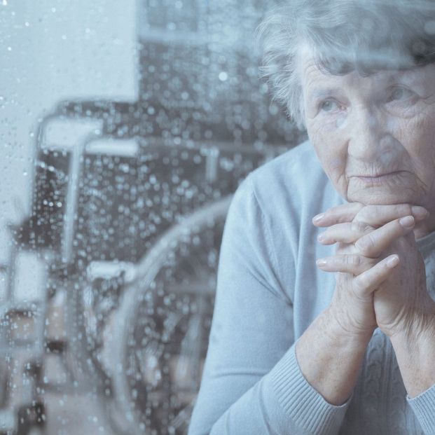 Una mujer con discapacidad mirando por la ventana