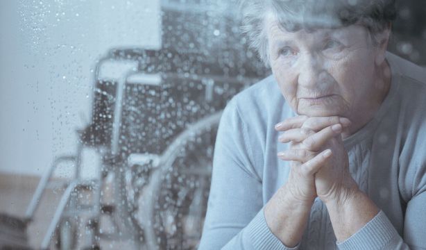 Una mujer con discapacidad mira por la ventana de su casa. (BIgstock)