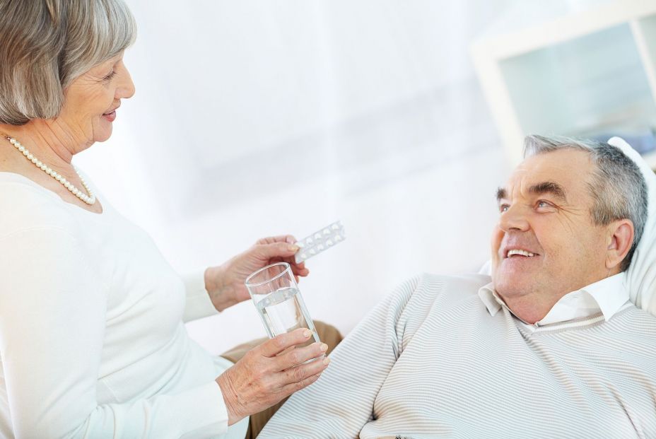 Una mujer da aspirina a su marido. (Bigstock) Una mujer da aspirina a su marido. (Bigstock)