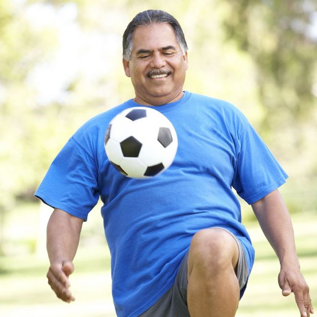 Hombre jugando al fútbol en el parque (BigStock)