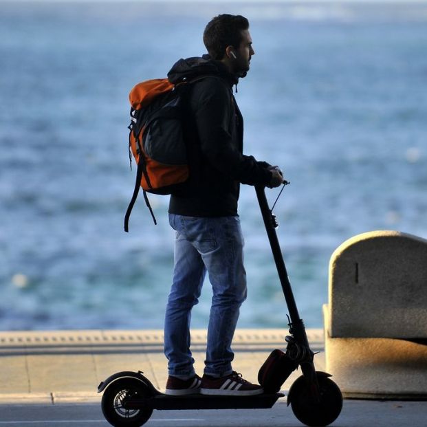 Un conductor de un patinete eléctrico con auriculares