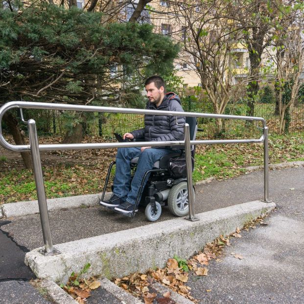 Persona en silla de ruedas por una rampa de acceso