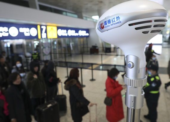 Personal del Aeropuerto Internacional de Tianhe en Wuhan (China) toma la temperatura a pasajeros 