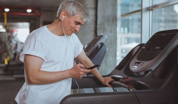 Sénior escuchando música mientras entrena (BigStock)