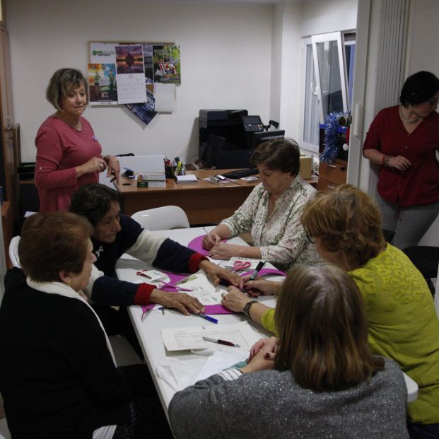 Las asistentes confeccionan un lazo morado por el 8-M.