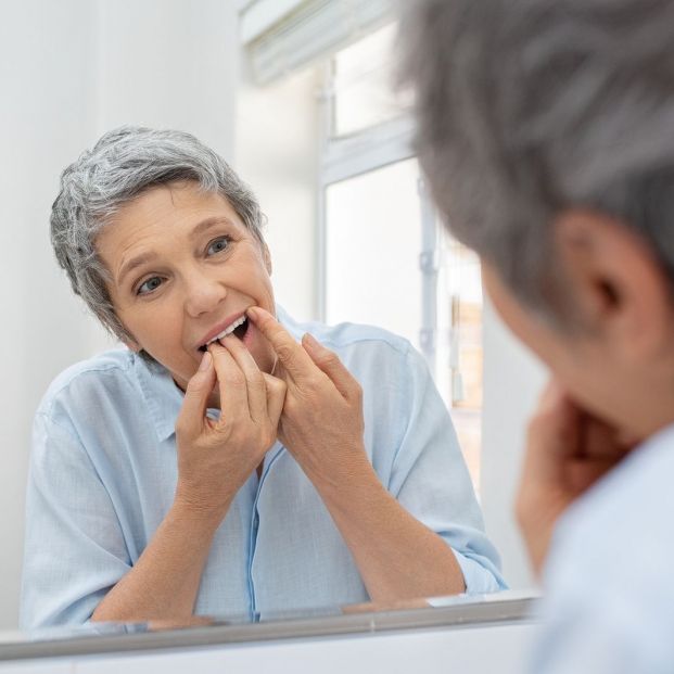 El uso del hilo dental en la limpieza de los dientes (bigstock)