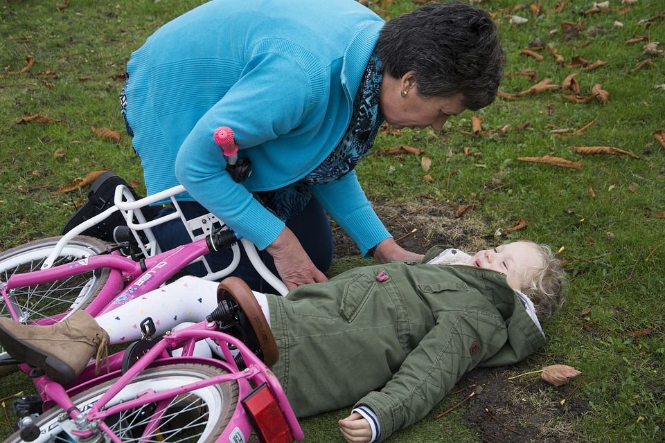 Primeros auxilios a una niña que se ha caído de una bicicleta (bigstock)