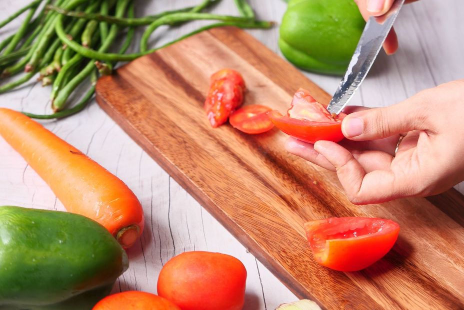 bigstock Hand Of Person Cutting Tomatoe 380919892