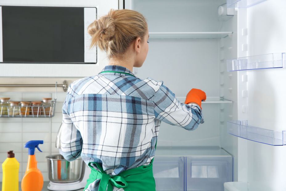 Mujer limpiando nevera para conservar los alimentos (bigstock)