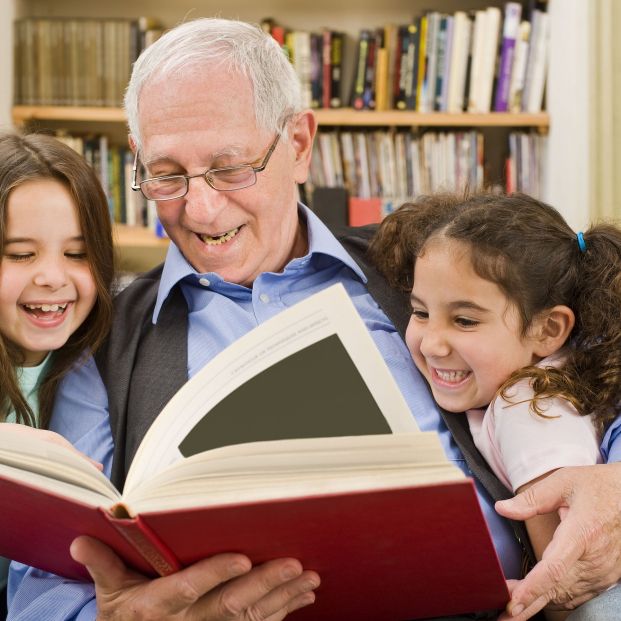 Abuelo leyendo con nietas (bigstock)