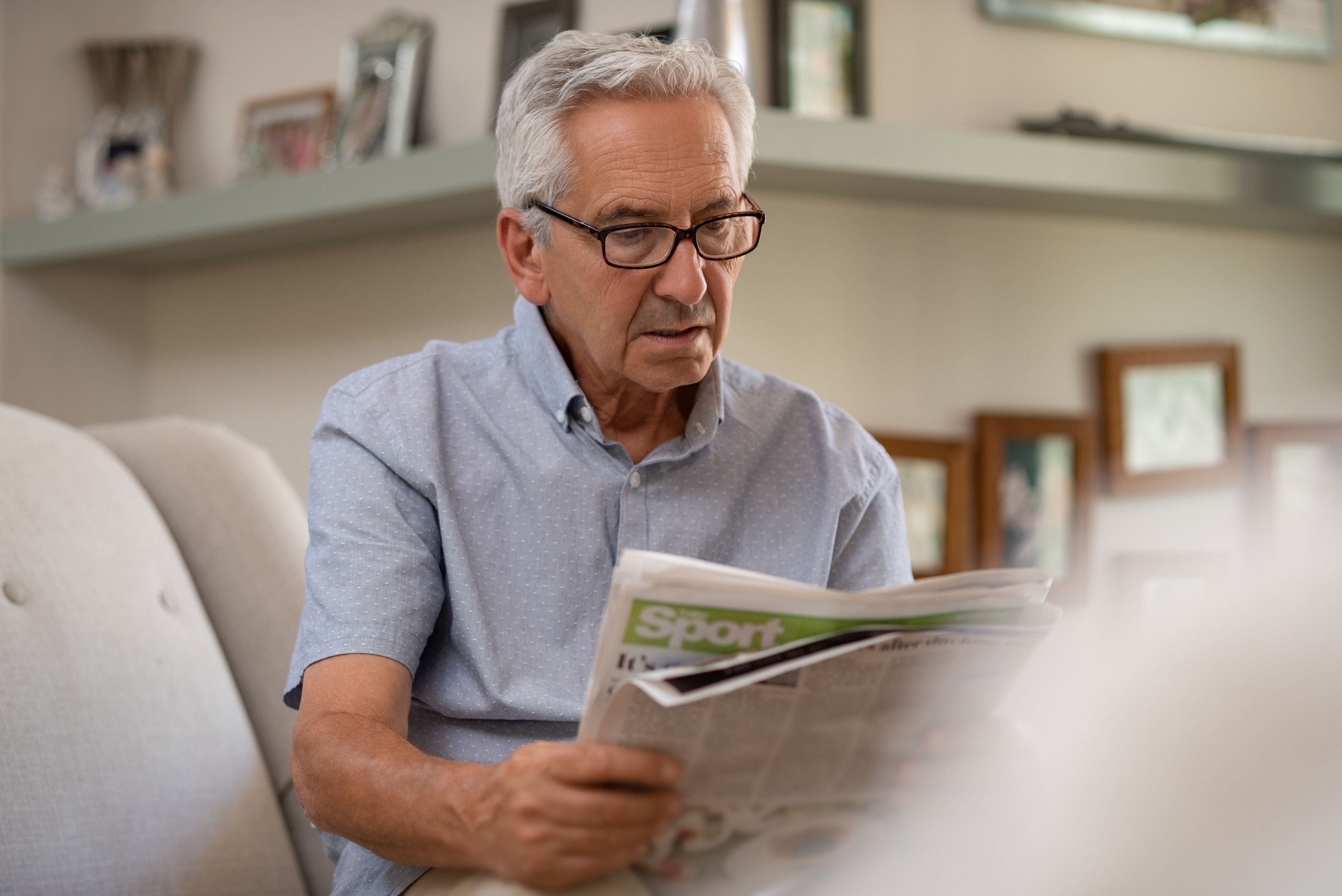 Consejos prácticos para cuidar la salud ocular. Persona adulta con gafas leyendo periódico a la distancia correcta (bigstock)