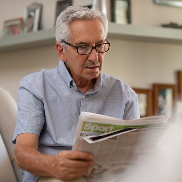 Persona adulta con gafas leyendo periódico a la distancia correcta