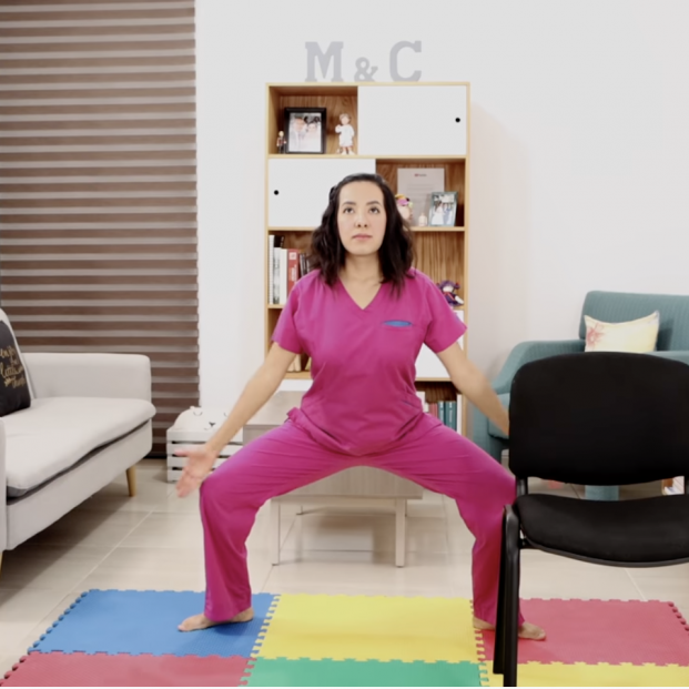 Ejercicio paso 1: baja el cuerpo flexionando las rodillas y, mientras que subimos, abre los brazos a la vez que sueltas el aire. (Captura de vídeo Fisioterapia Querétaro)