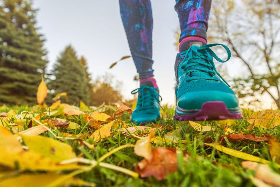 Mujer caminando con zapatillas de deporte por superficie cubierta de hojas. Bigstock