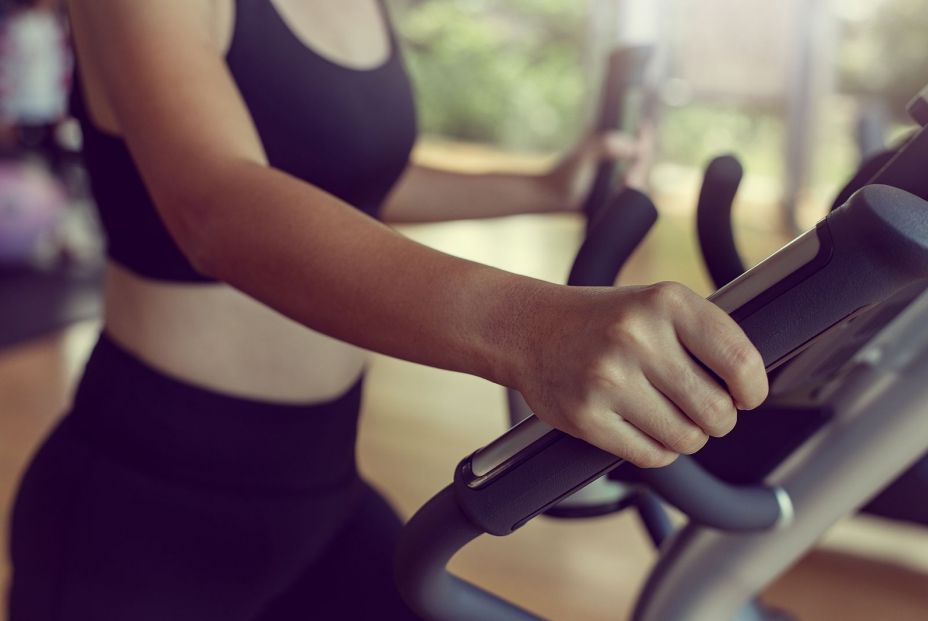 Mujer agarrándose al manillar de la cinta de correr. Foto: Bigstock 