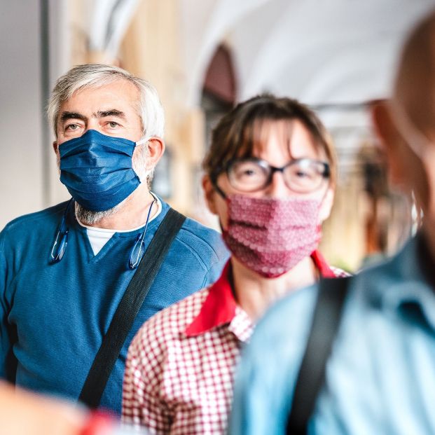 Adultos caminando por la calle con mascarilla (BigStock)