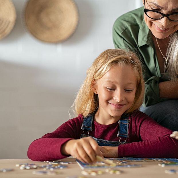 Mujer haciendo un puzzle con su nieta bigstock