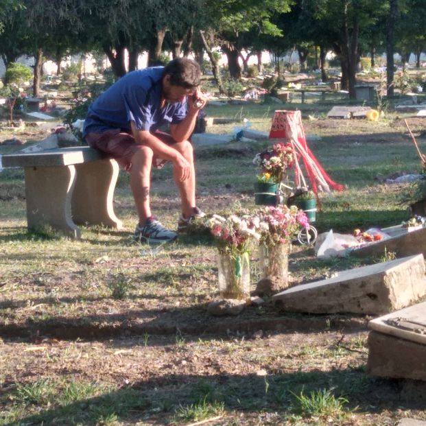 La historia detrás de la imagen viral de un hombre escuchando un partido junto a la tumba de su hijo