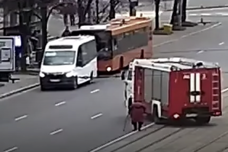 Los bomberos cortan con su camión una avenida para ayudar a cruzar a una mujer mayor con muletas