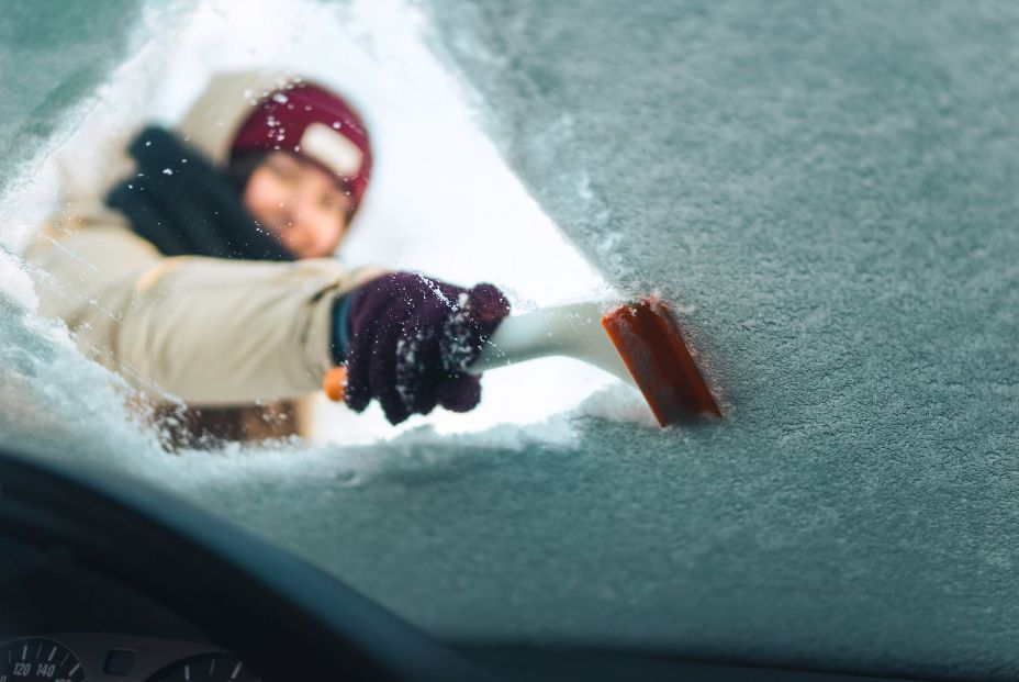 mujer quitando hielo parabrisas